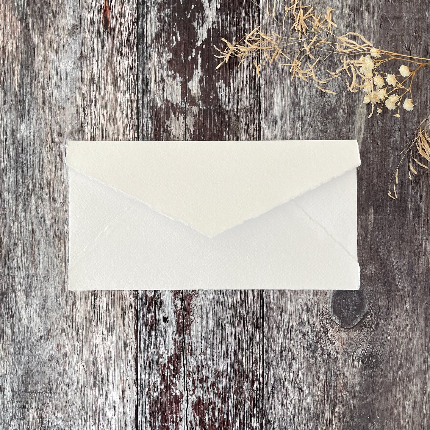 Handmade paper envelopes made from recycled cotton rag paper in white.  DL size invitation envelopes with a deckled edge and pointed flap.  By The Natural Paper Company