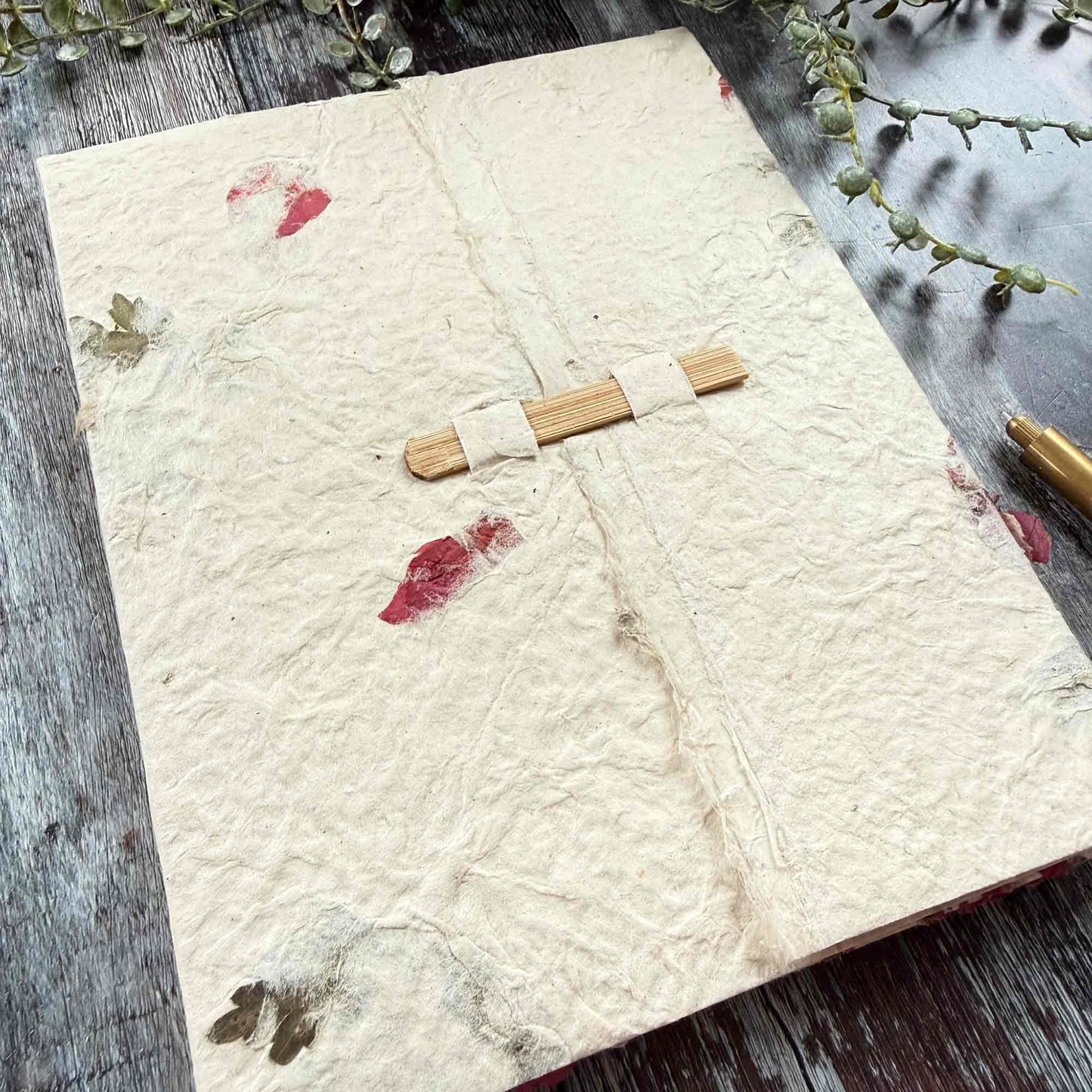 Close-up of Lokta paper folder bamboo closure detail, textured handmade paper with natural leaf and petal inclusions