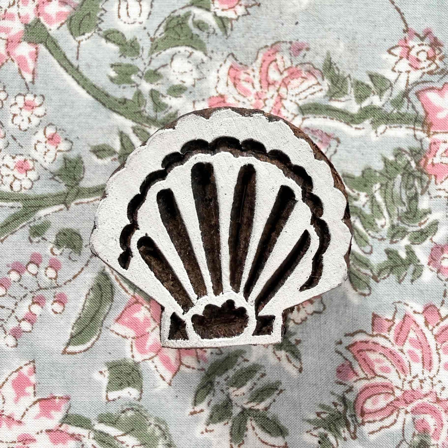 Indian wood block stamp — Shell scallop seashell resting on block printed fabric, graceful curved ribs and scalloped rim, hand-carved wooden stamp, authentic traditional printing block from India