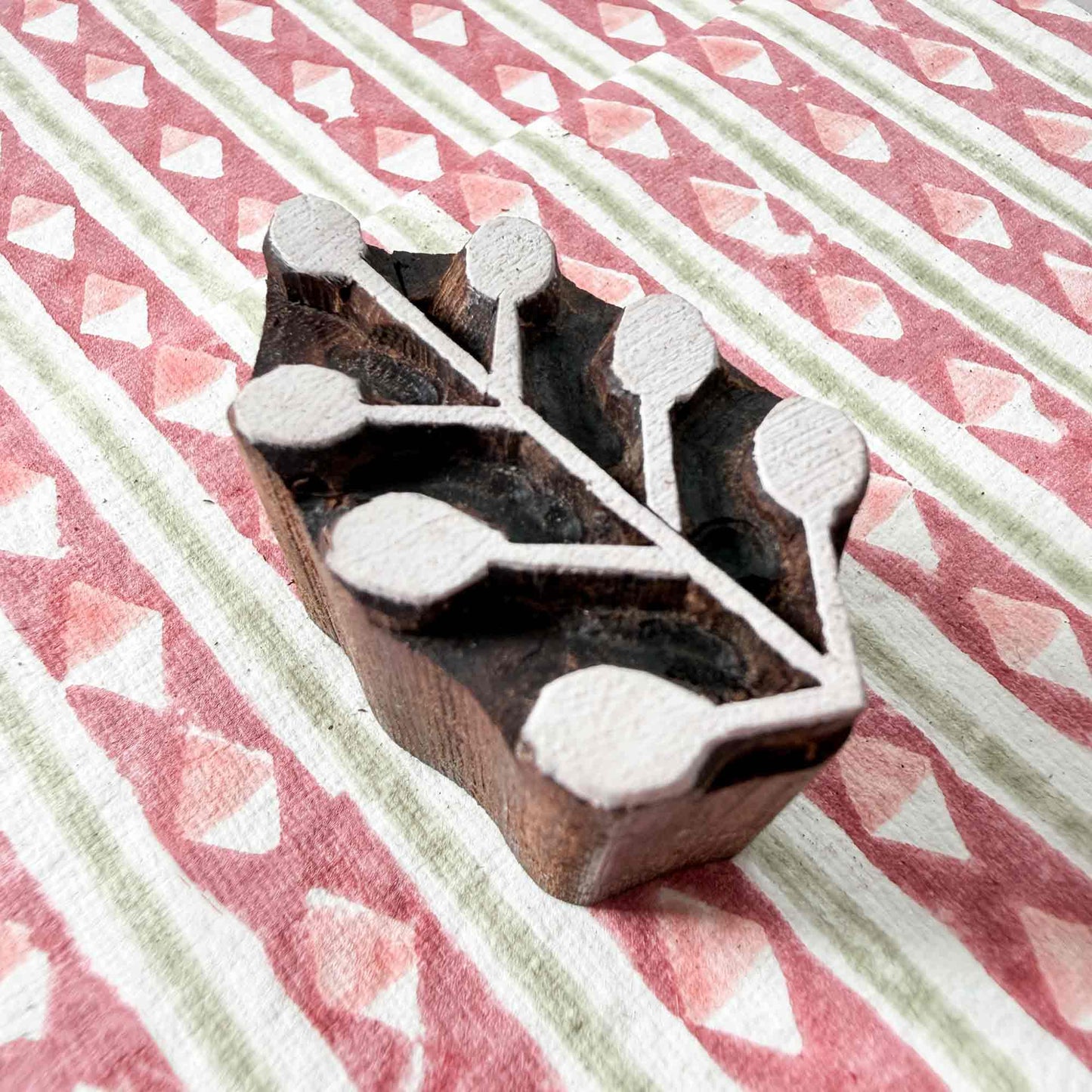 Sprig wooden stamp — branching berry sprig resting on block printed fabric, six rounded berries on graceful stems, handcrafted Indian printing block ready for printing