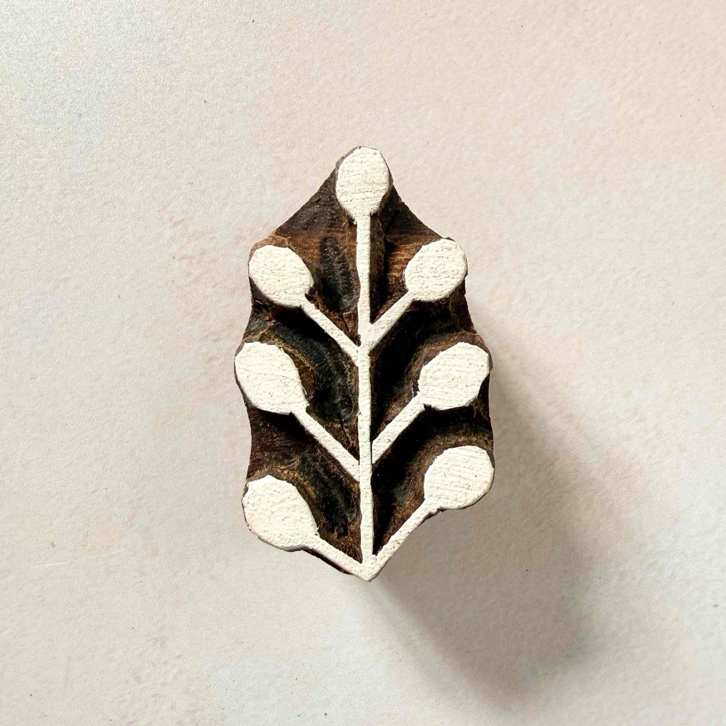 Sprig Indian wood block stamp — sweet berry sprig face-on view on soft pale background, symmetrical branching stem with six round berries, hand-carved traditional printing block