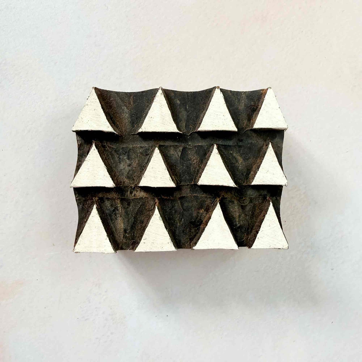 Tiptop wooden stamp — neat triangular repeat pattern face-on view on soft pale background, three orderly rows of pointed shapes, handcrafted Indian printing block designed for seamless repeats