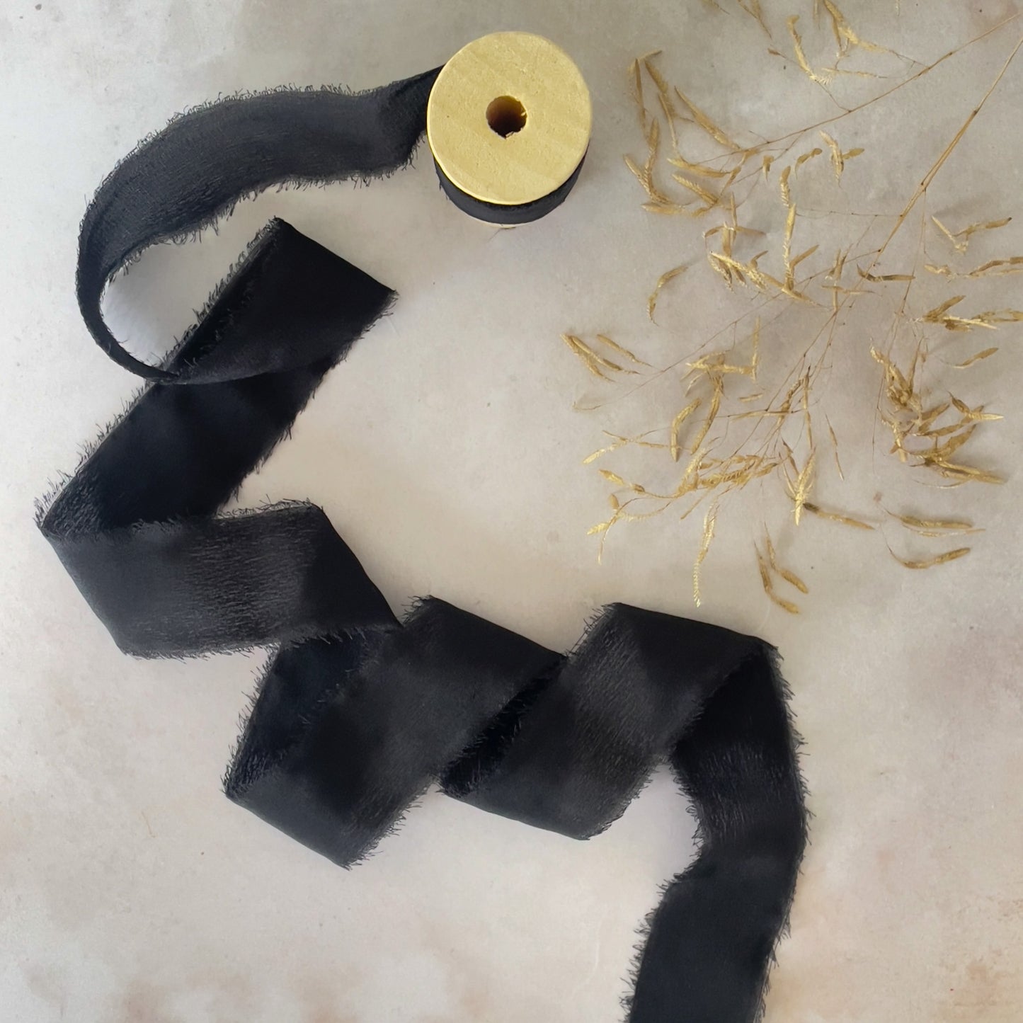 Black silk ribbon for crafts.  Roll of Habotai silk ribbon on a wooden spool.  Raw edge silk for decorating wedding invitations, stationery and crafts.  By The Natural Paper Company