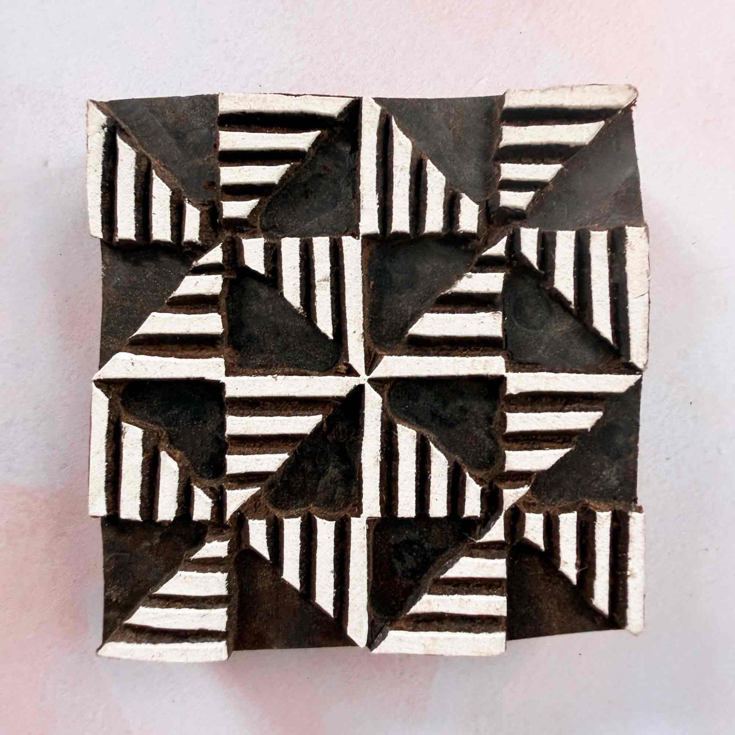 Windmill wooden stamp — bold eight-segment geometric design face-on view on soft pale background, lined segments radiating from centre, handcrafted Indian printing block