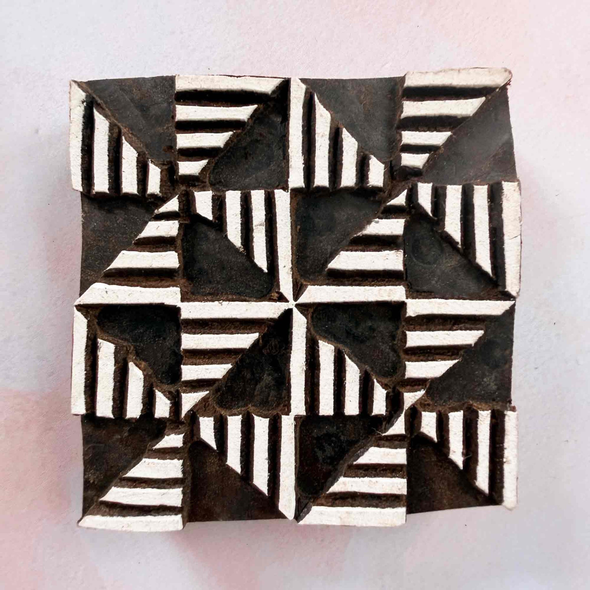 Windmill wooden stamp — bold eight-segment geometric design face-on view on soft pale background, lined segments radiating from centre, handcrafted Indian printing block