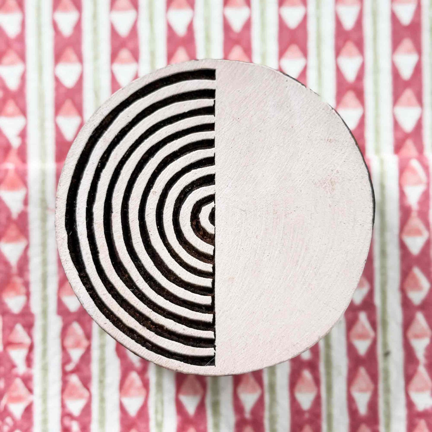 Indian wood block stamp — Yin design, split circle with concentric arcs resting on a block printed fabric, hand-carved wooden stamp, authentic traditional printing block from India
