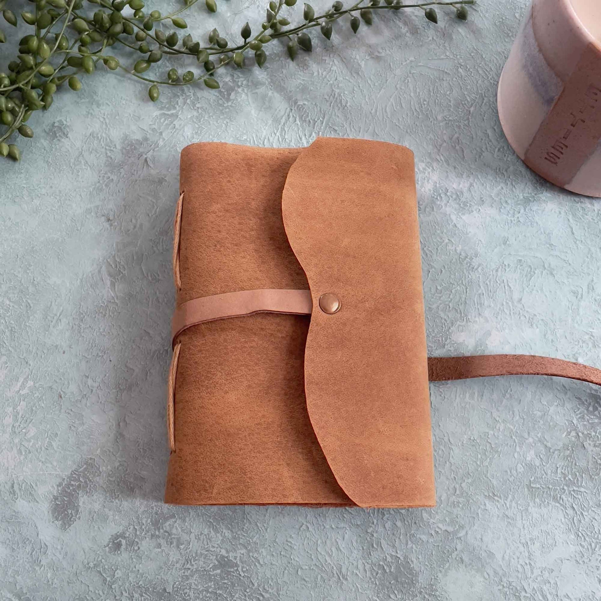 Small tan leather note book with a front tie.  A perfect gift.  Made by hand