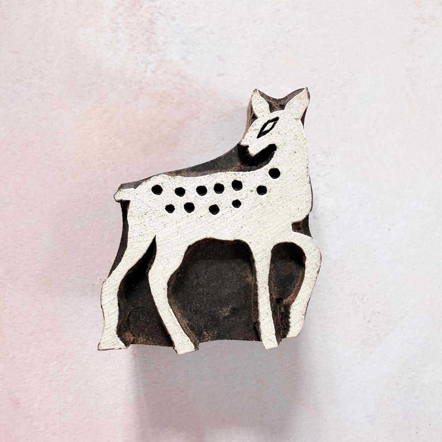 Indian wood block stamp — Bambi spotted deer face-on view on soft pale background, graceful fawn with ten neat spots, hand-carved wooden stamp, authentic traditional printing block from India