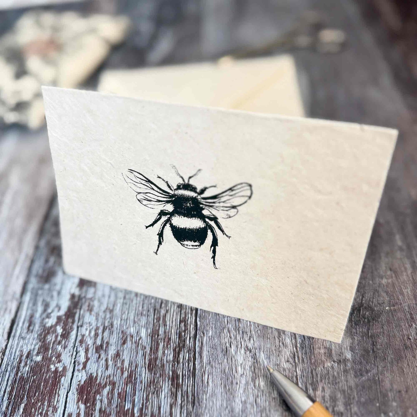 Close up of hand screen printed bumble bee illustration on textured natural Lokta paper card
