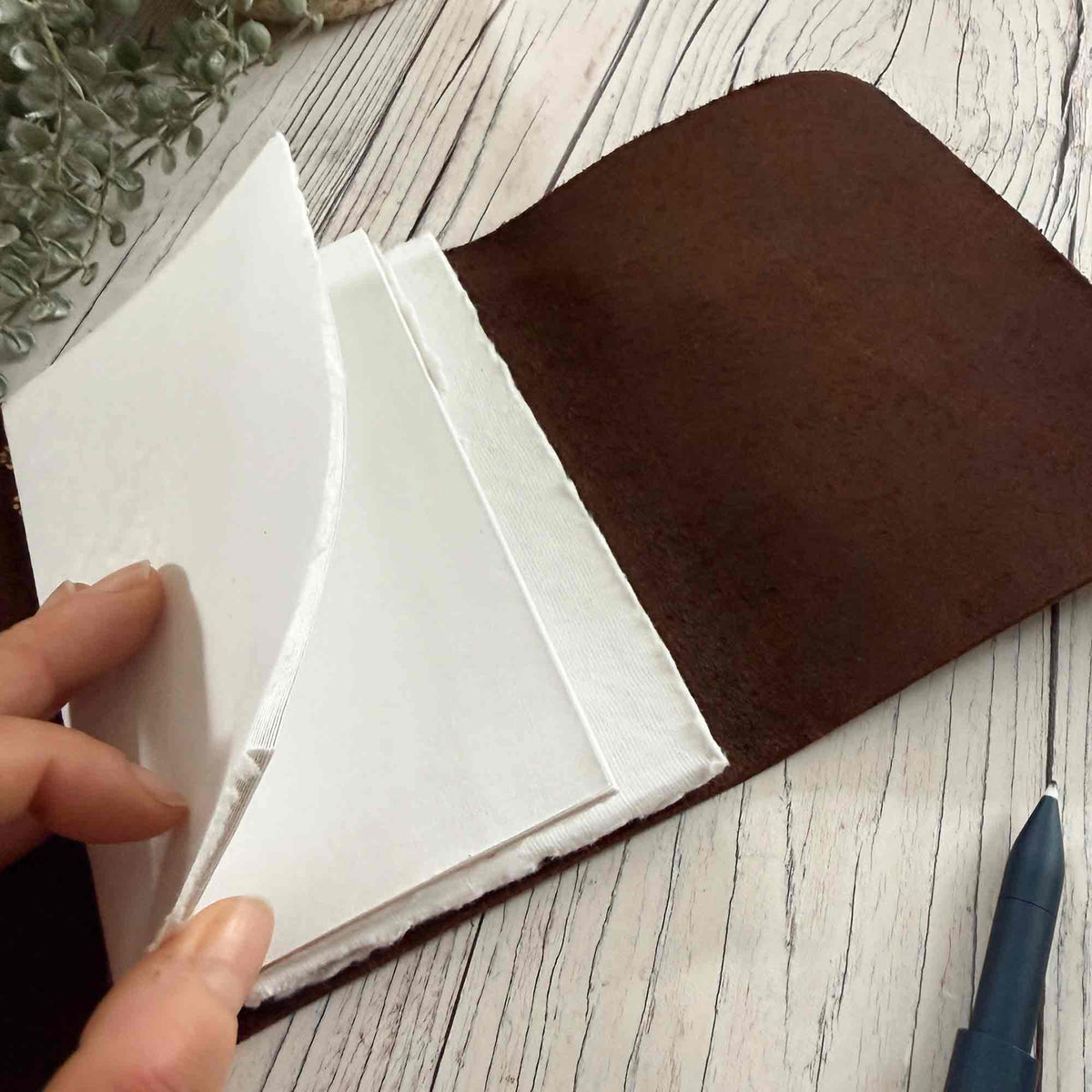 Brown refillable leather notebook showing removable A6 paper inserts
