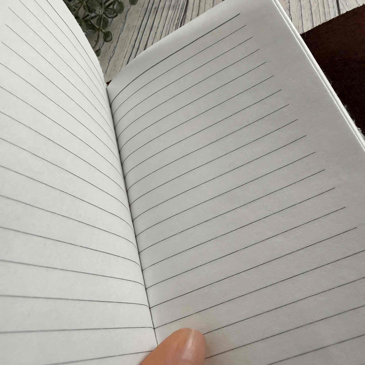 A6 brown refillable leather notebook open to lined cotton paper pages