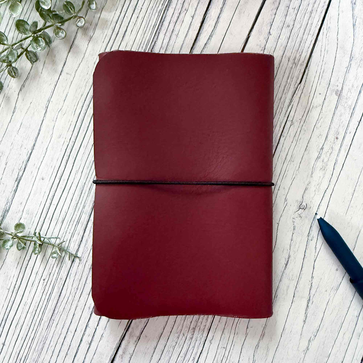 Handmade burgundy A6 refillable leather notebook with black elastic closure