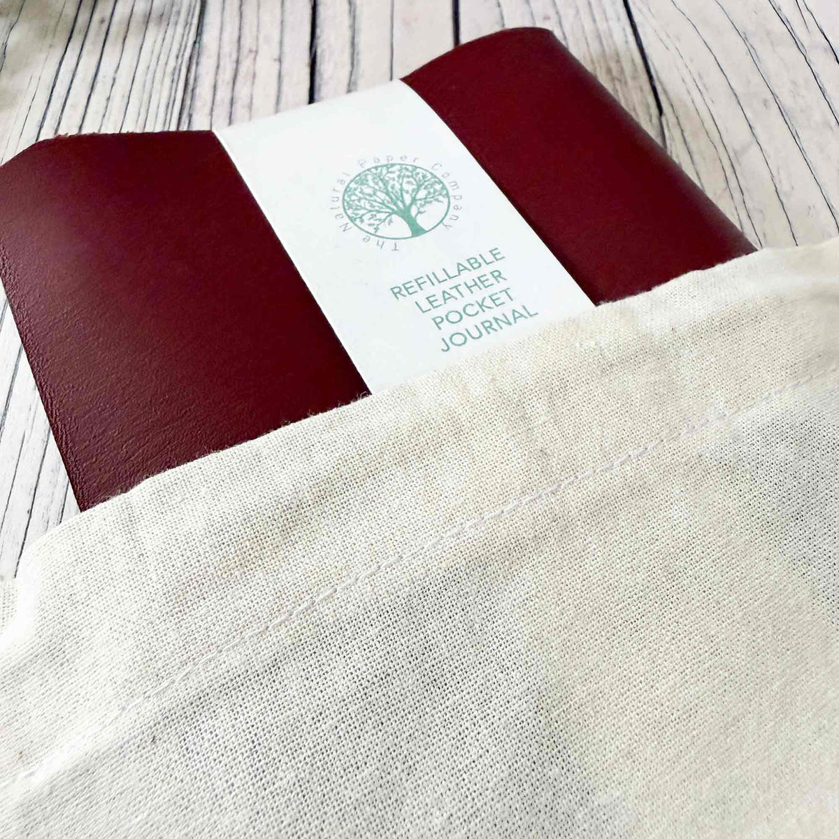 Burgundy A6 refillable leather journal presented in Natural Paper Company drawstring gift bag