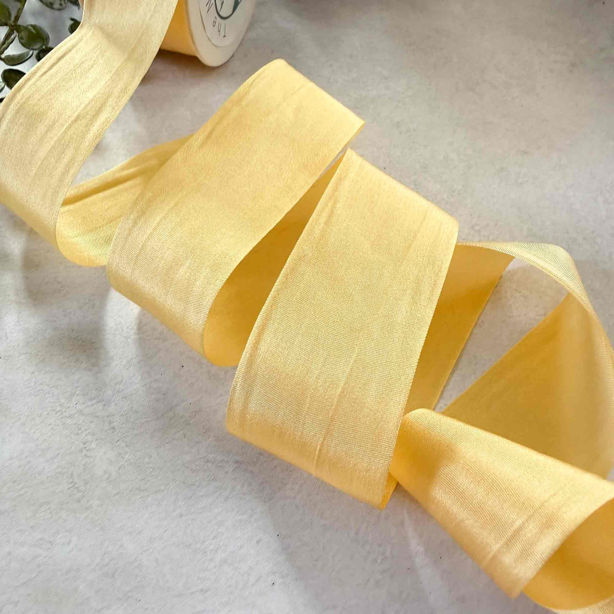 Buttermilk Silk Ribbon in soft pale yellow with a luxurious sheen and wide 32.5mm closed-edge finish.
