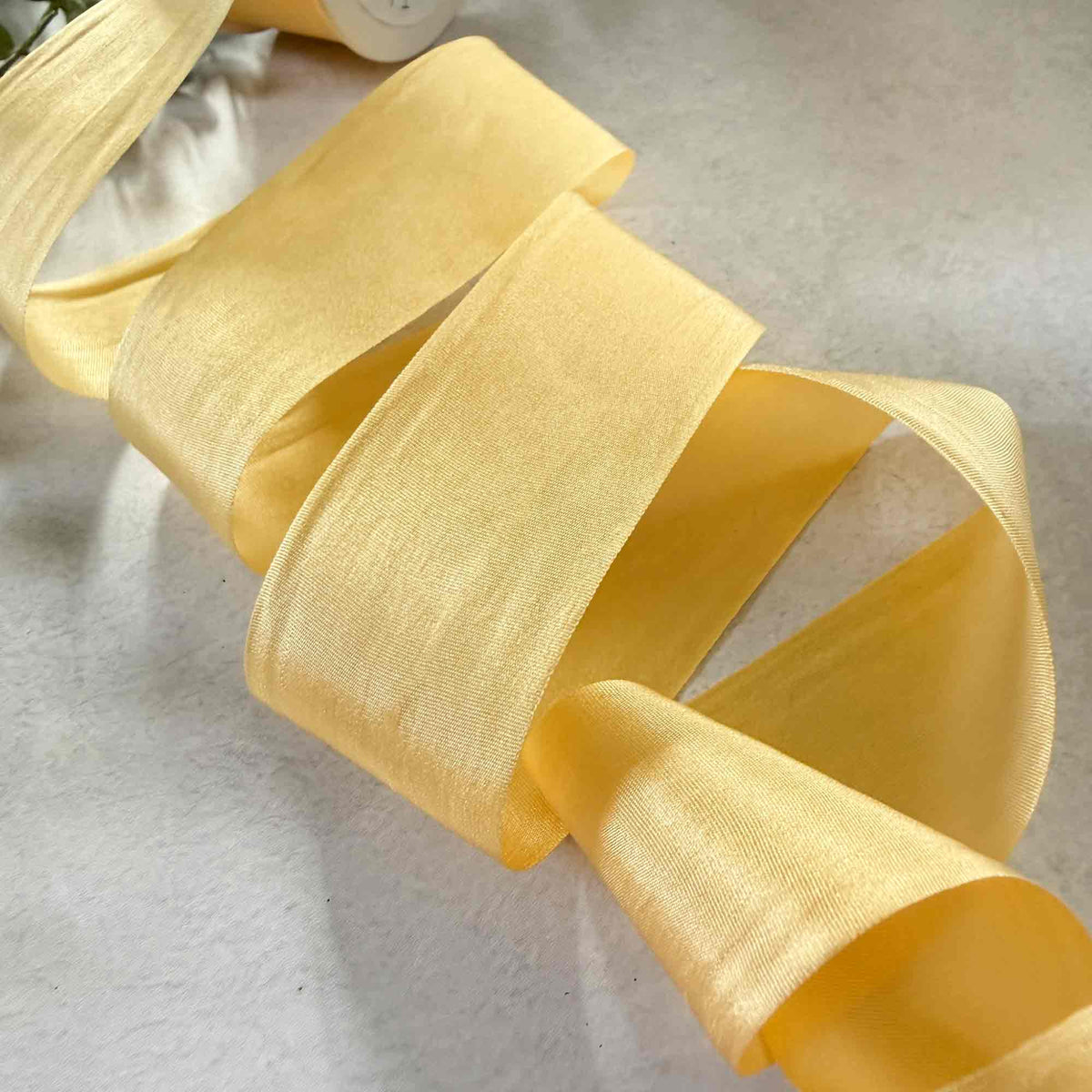 Buttermilk pale yellow Silk Ribbon showing its smooth Habotai texture and elegant closed edges.