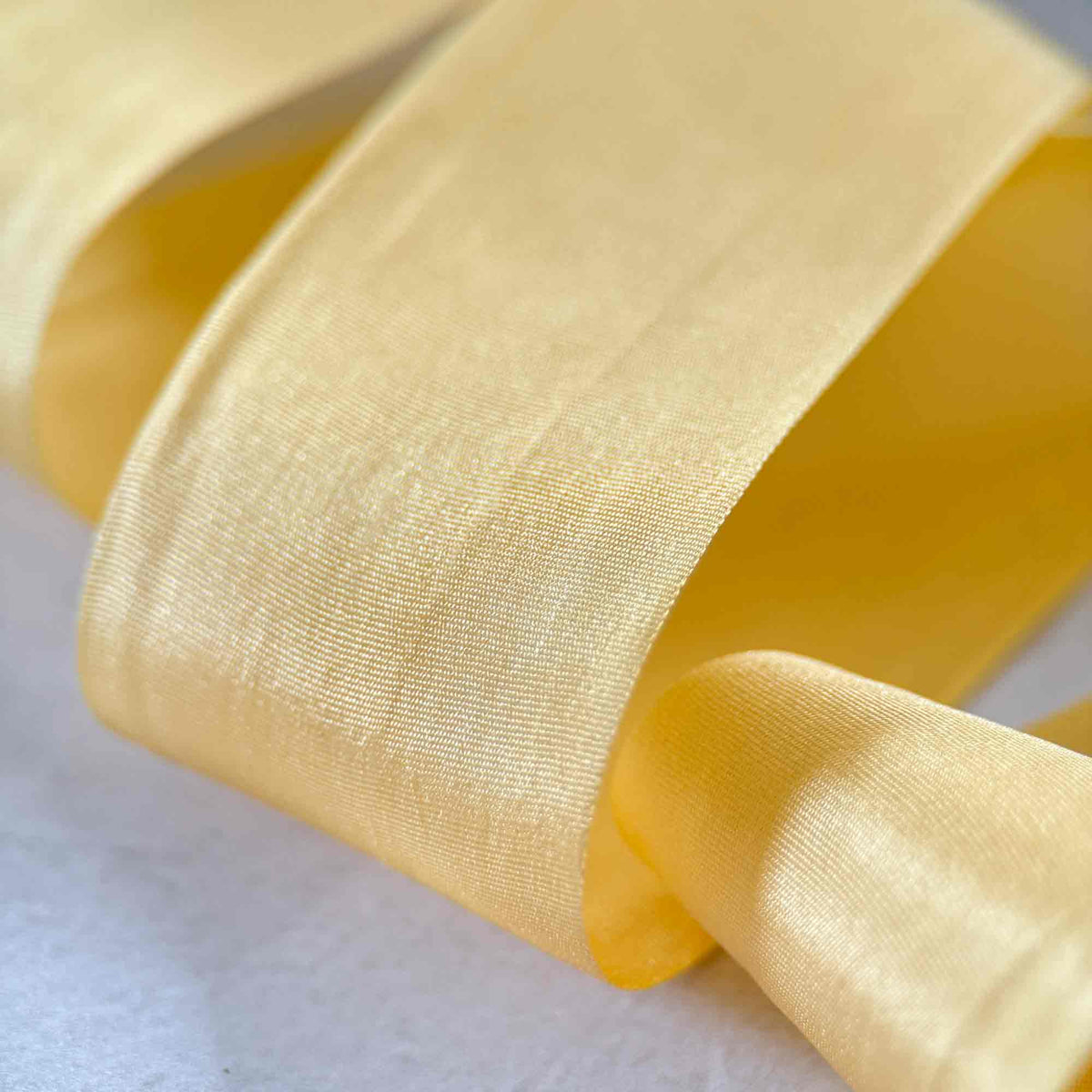 Close-up of wide Buttermilk Silk Ribbon showing its fine weave, natural sheen, and creamy yellow colouring.
