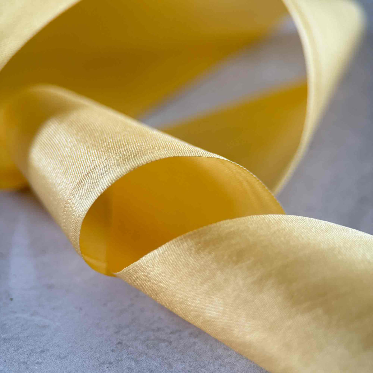 Buttermilk Habotai Silk Ribbon in soft pale yellow with a luxurious 32.5mm wide closed-edge finish.