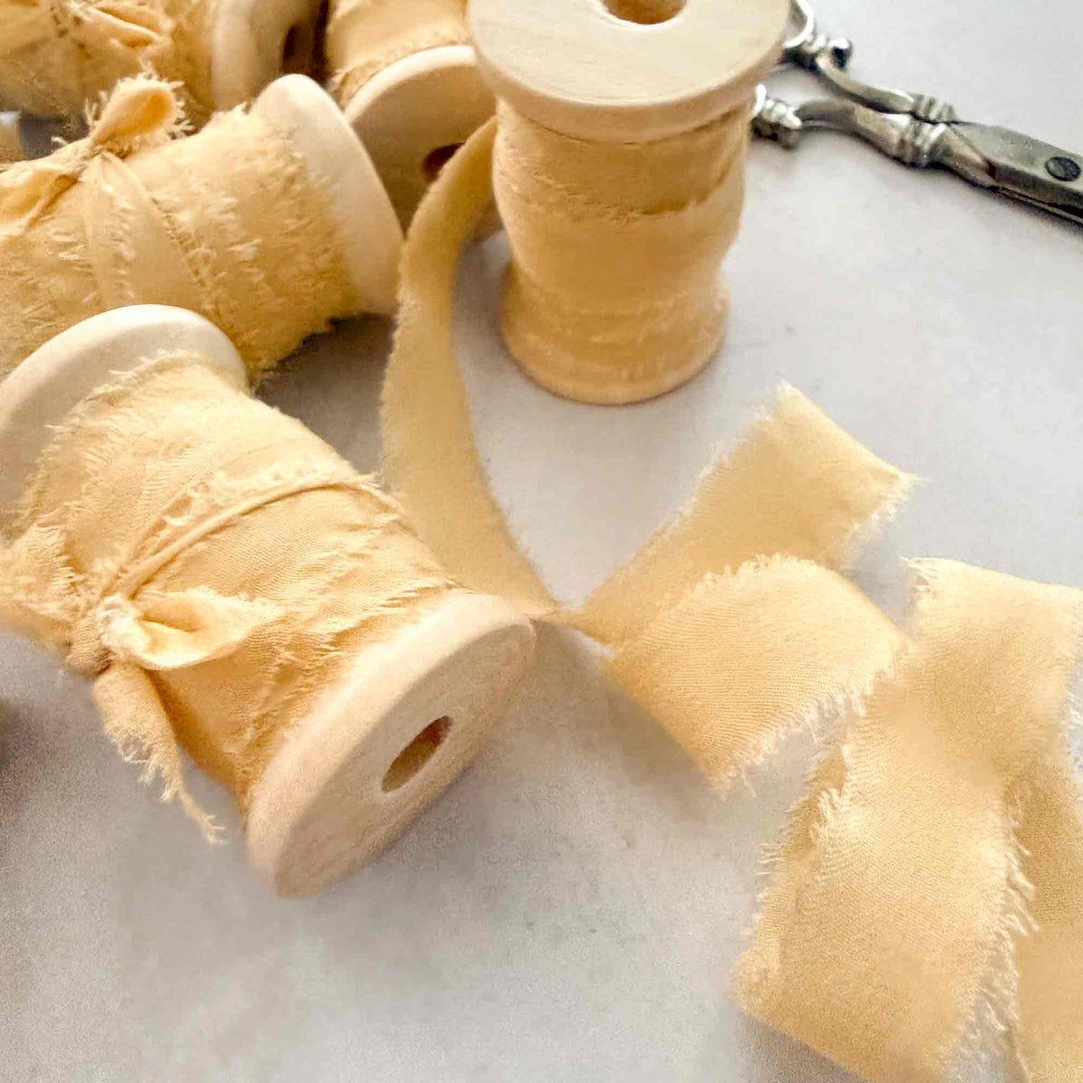 Buttermilk 10mm silk ribbon with softly frayed raw edges and wooden reels