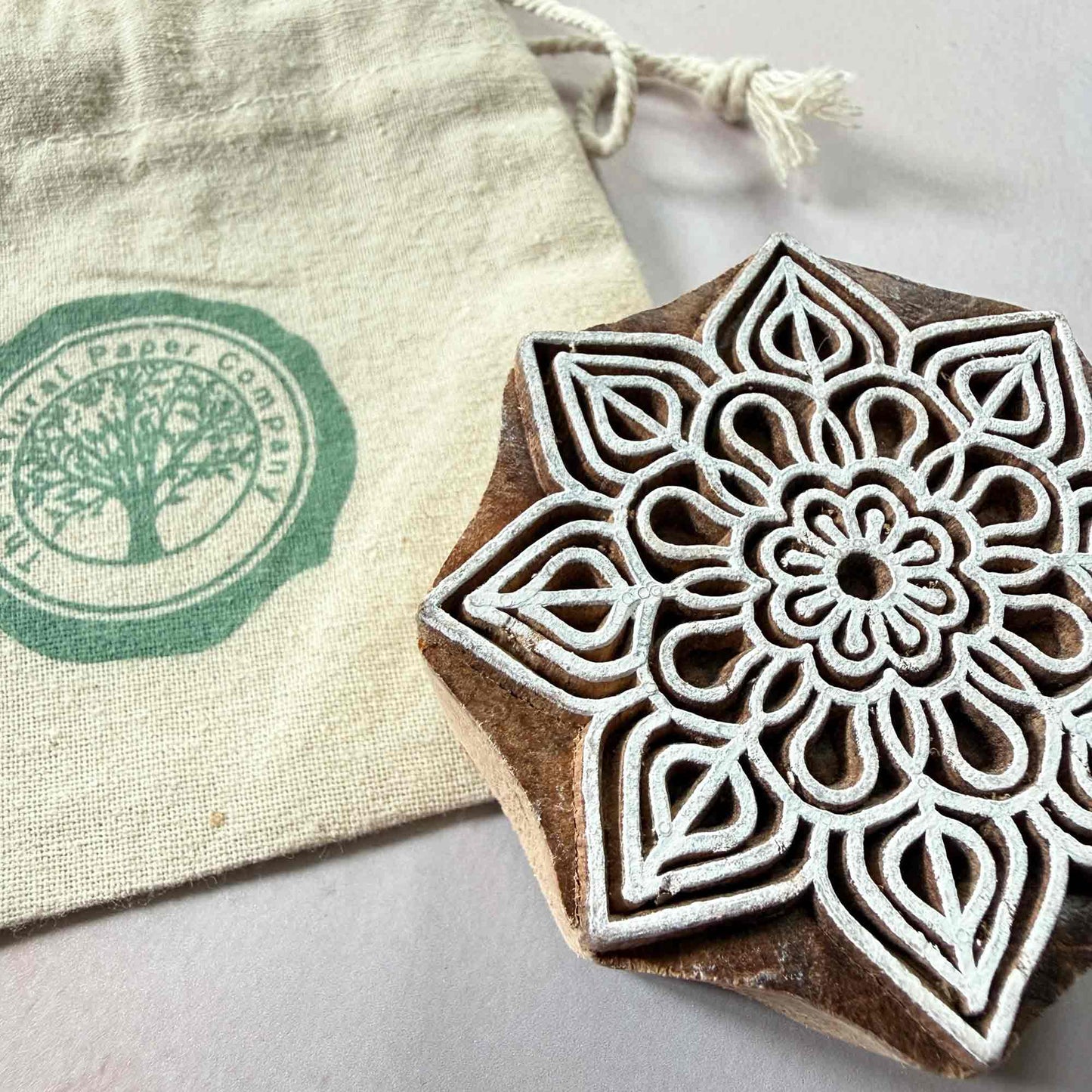 Wooden stamp with floral design next to a branded gift bag