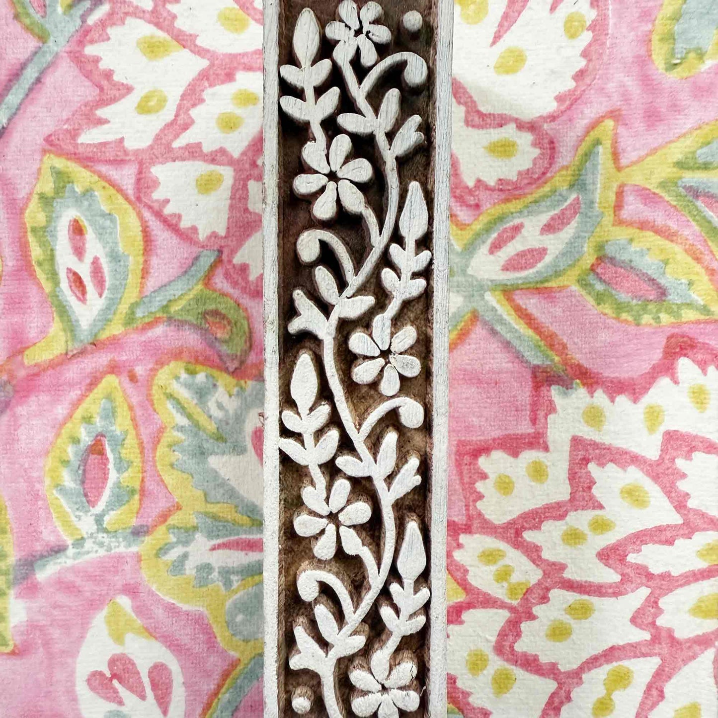 Decorative wooden block with floral pattern on a pink and white floral background
