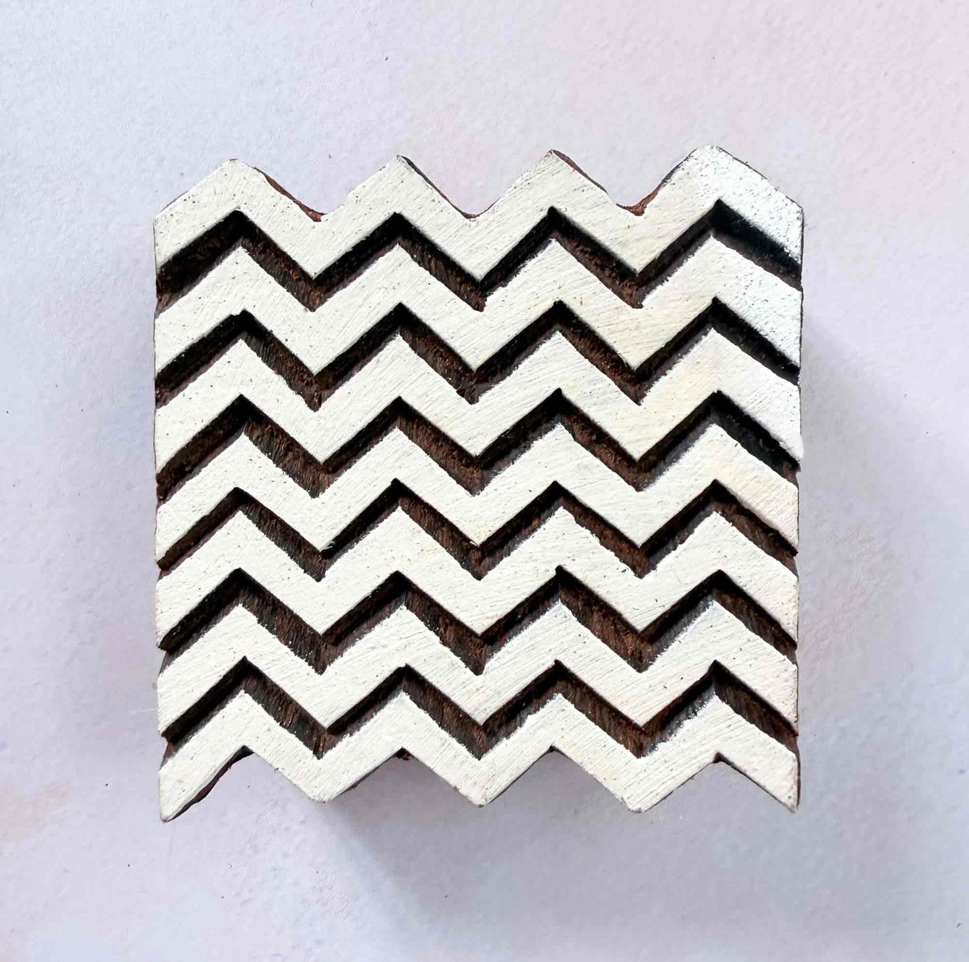 Chevron wooden stamp — graceful zigzag repeat pattern face-on view on soft pale background, seven aligned V-rows forming seamless design, handcrafted Indian printing block
