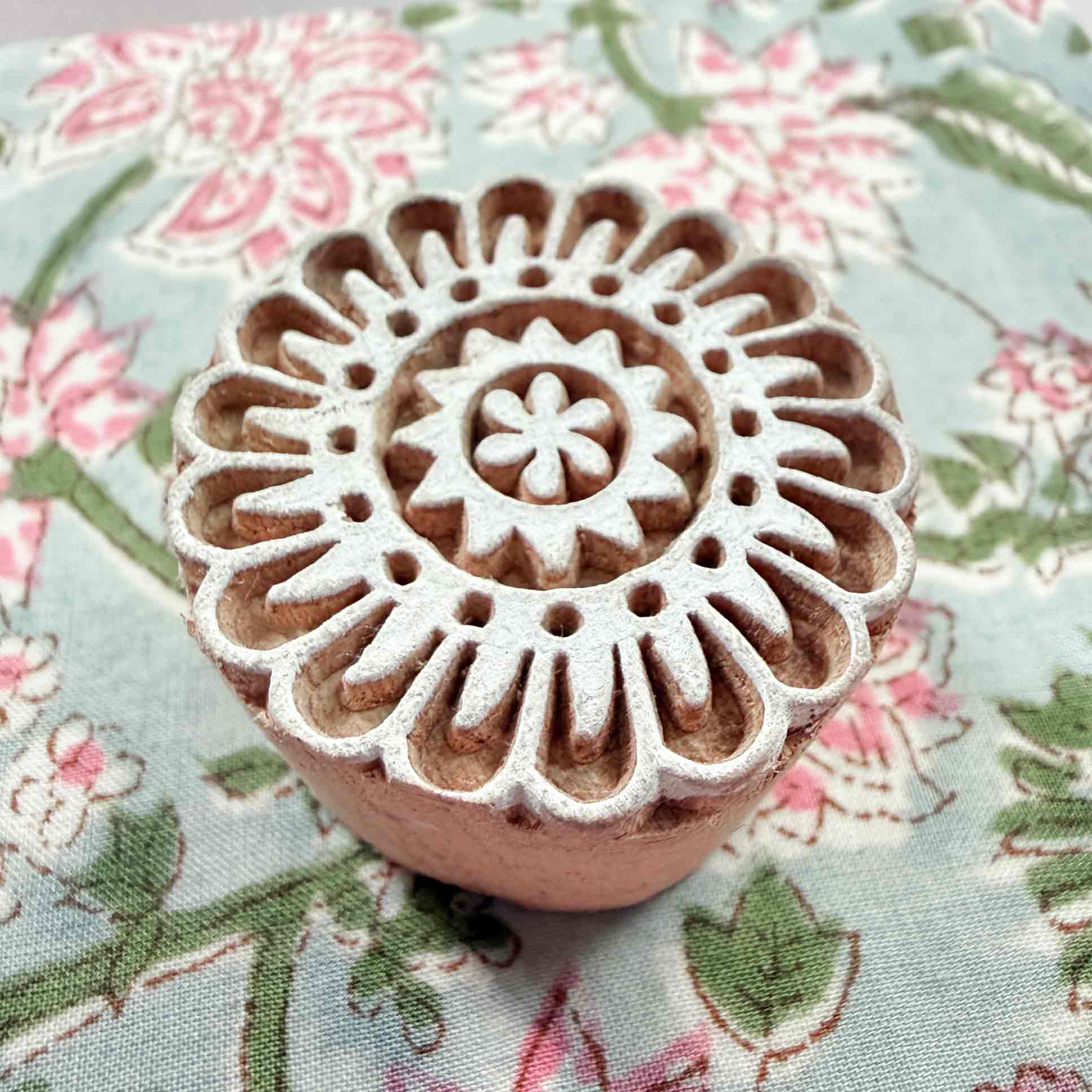 Corolla Indian wood block stamp resting on floral block-printed fabric — fabric printing tool