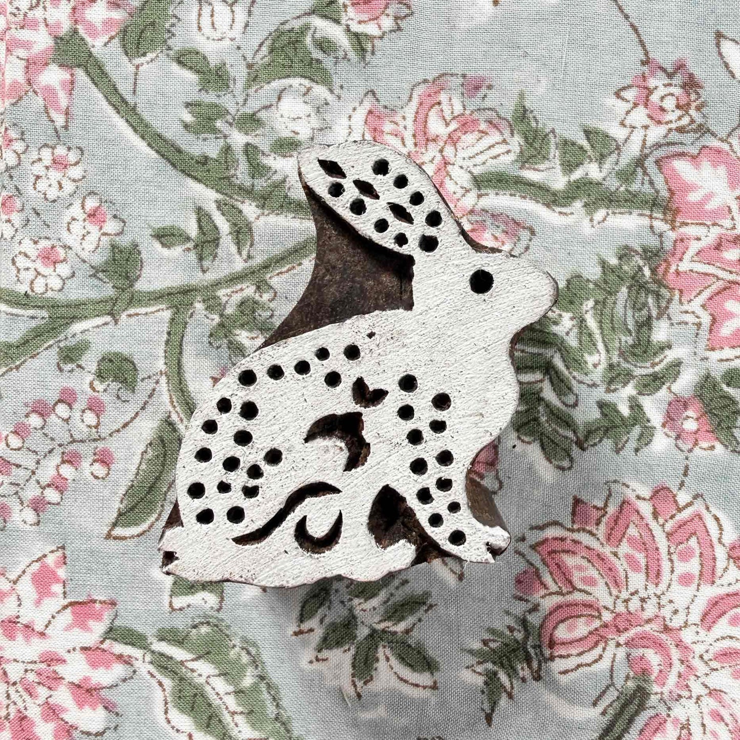 Indian wood block stamp — Cottontail spotted rabbit resting on block printed fabric, graceful seated hare with dotted body, hand-carved wooden stamp, authentic traditional printing block from India