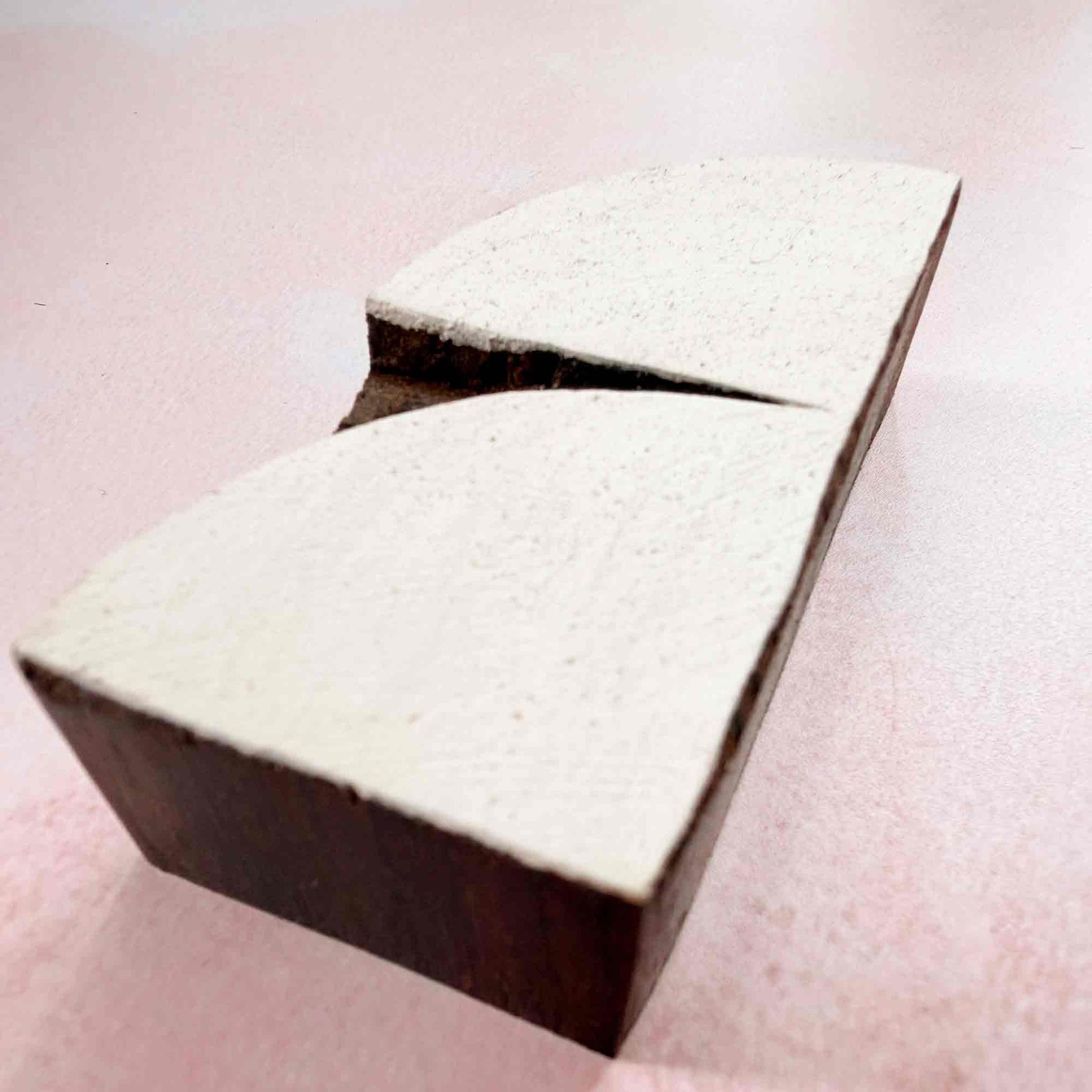 Hand-carved Crescent Indian wood block stamp — split-curve arch design viewed from side on soft pale background, traditional printing block close-up
