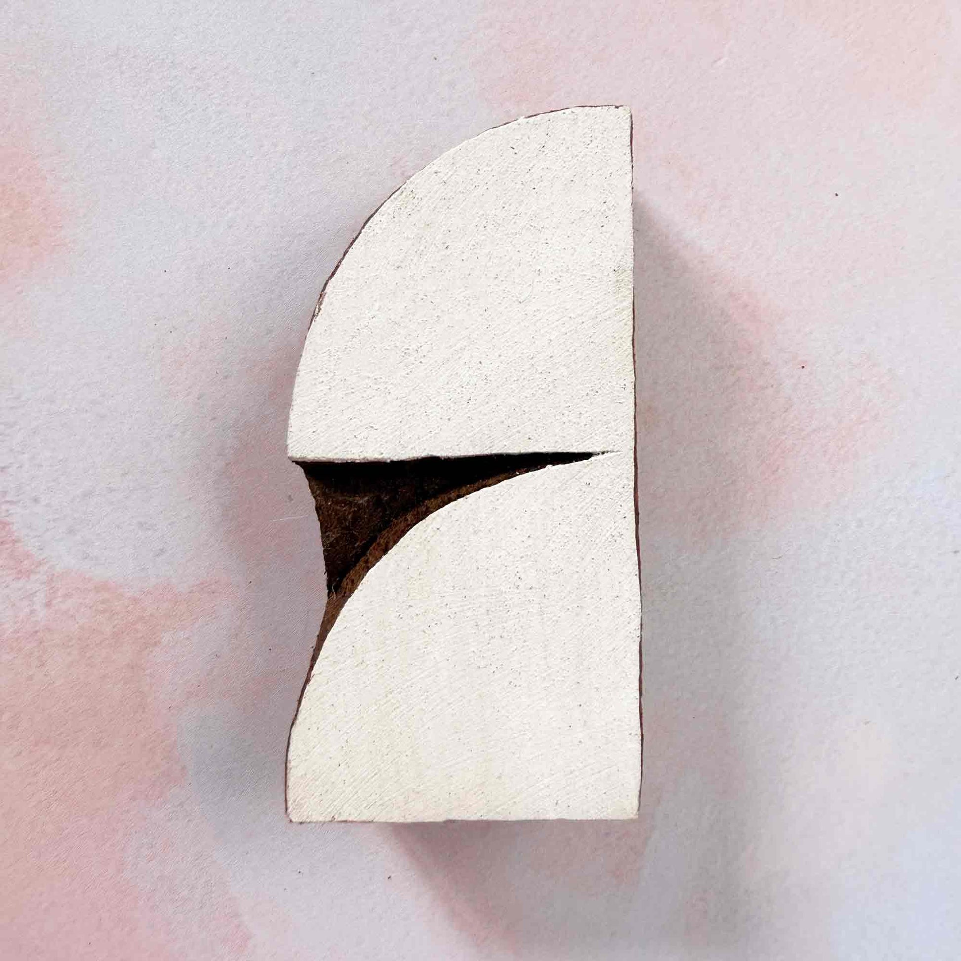 Crescent Indian wood block stamp — elegant split-curve arch face-on view on pale background, hand-carved traditional printing block