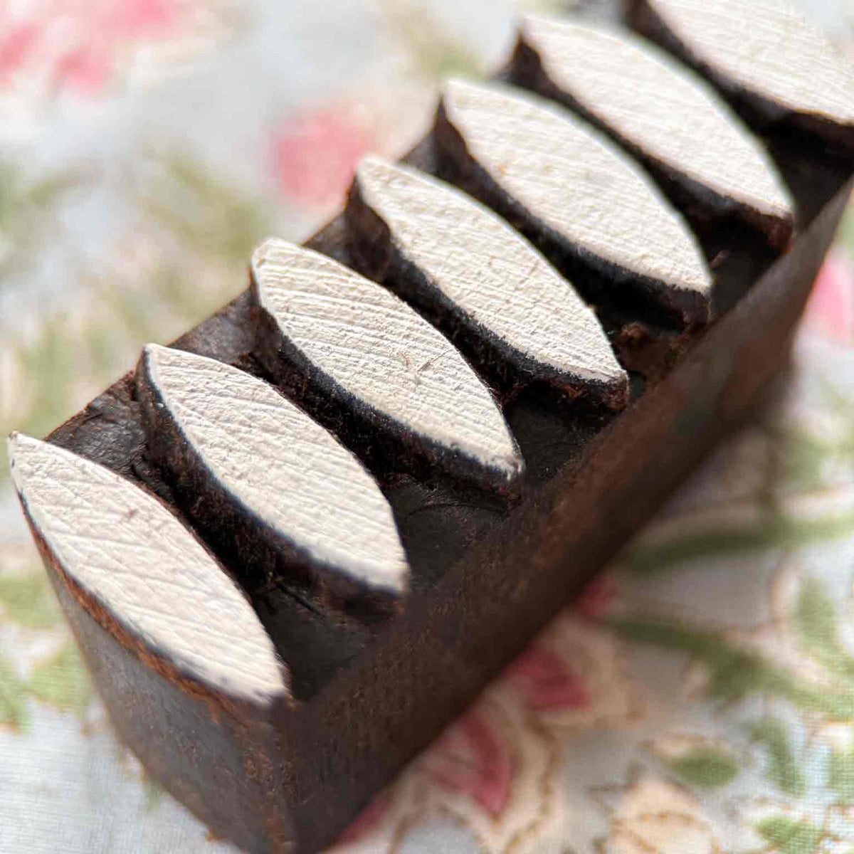 Close-up of Dana hand-carved wooden printing block showing the raised leaf-shaped printing surfaces and natural wood texture.