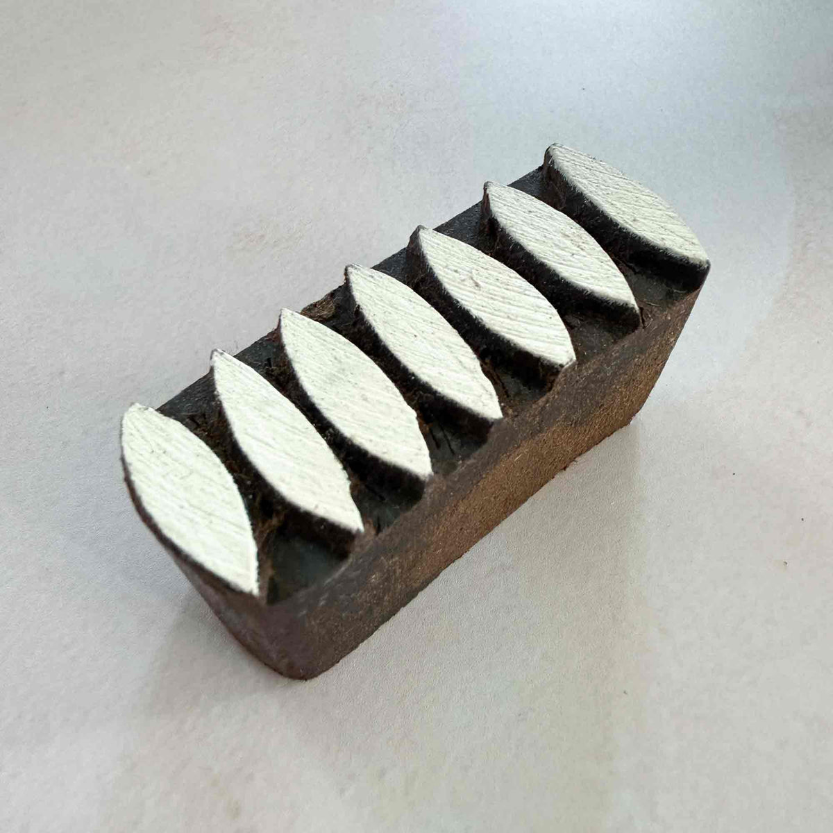 Angled view of Dana Indian wooden stamp featuring a row of seven geometric leaf-shaped motifs for border and repeat printing.