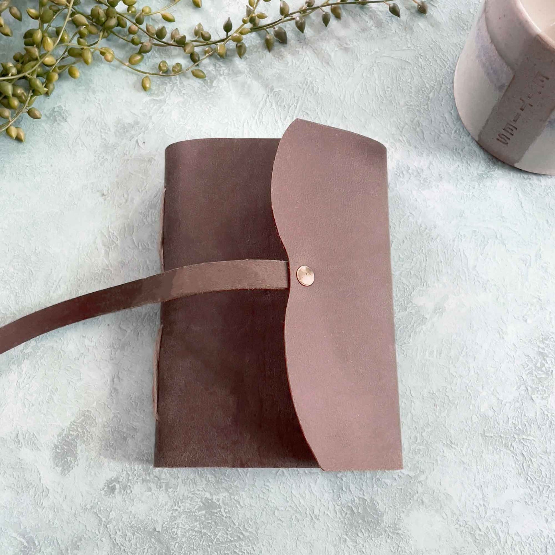 small handmade leather note book with tie.  Made from dark brown leather and recycled cotton rag paper
