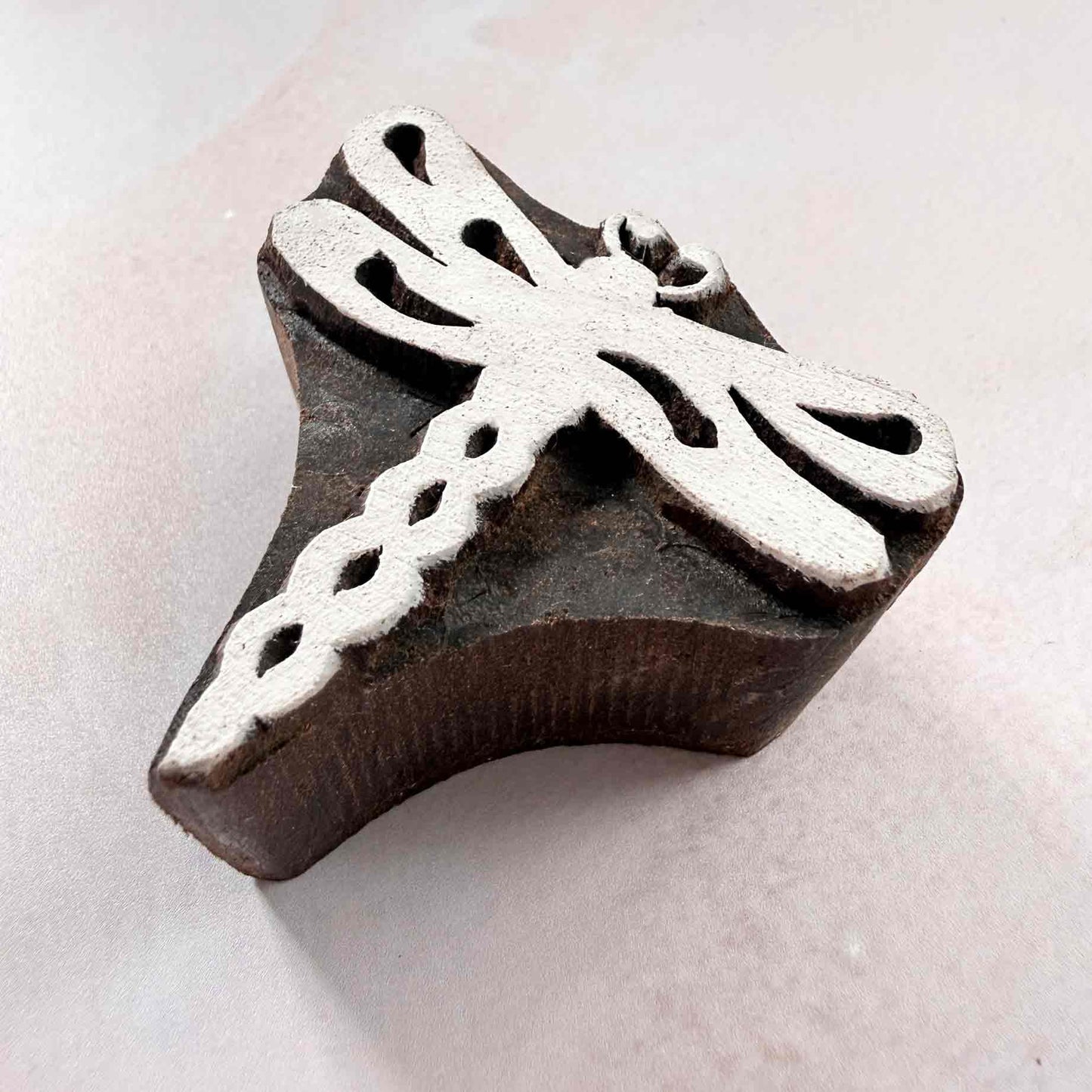 Hand-carved dragonfly wooden stamp shown from an angled side view