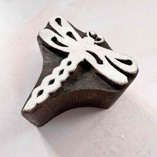Hand-carved dragonfly wooden stamp shown from an angled side view
