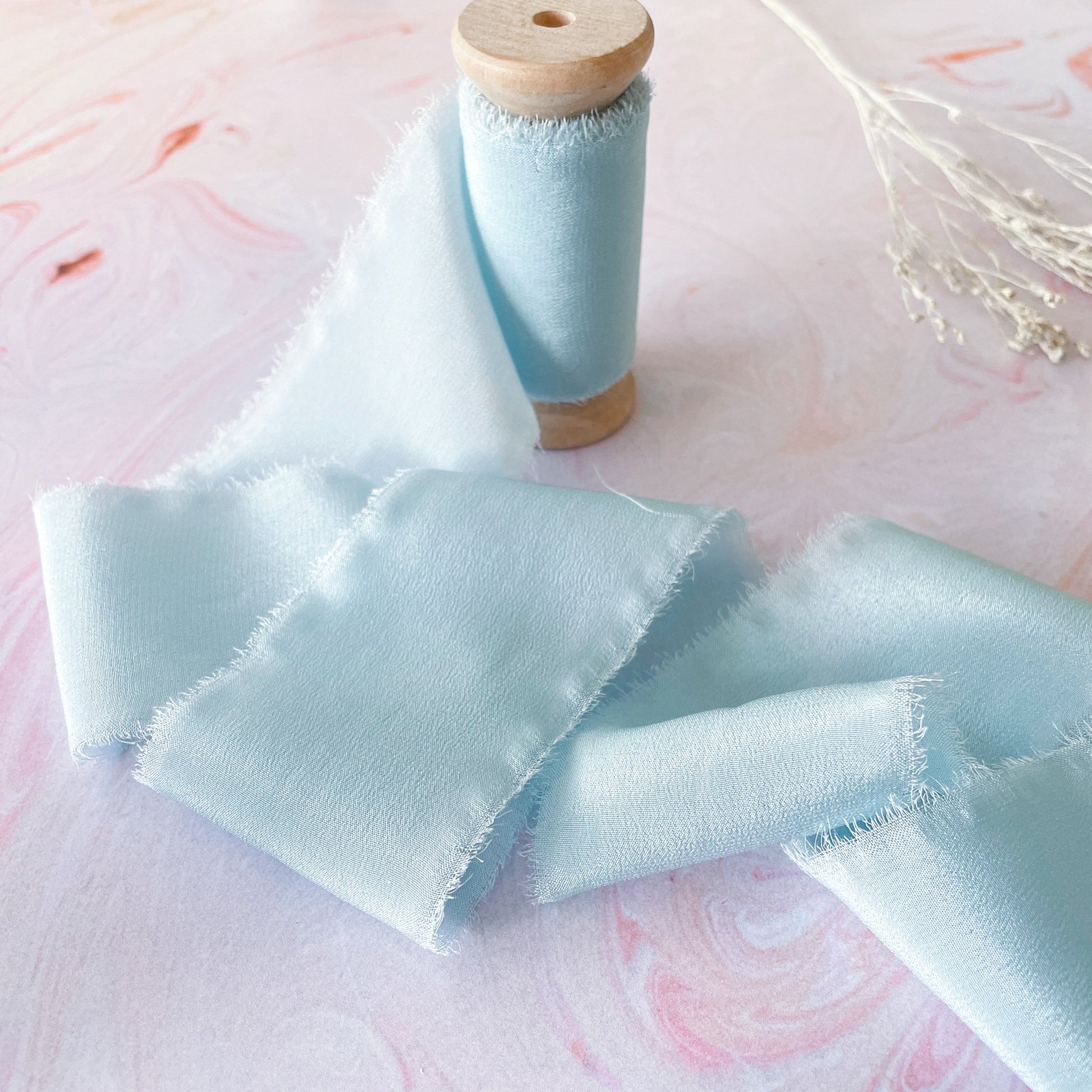 Pastel colour silk ribbon on a wooden reel.  Luxury silk ribbon in aquamarine colour.  By The Natural Paper Company.