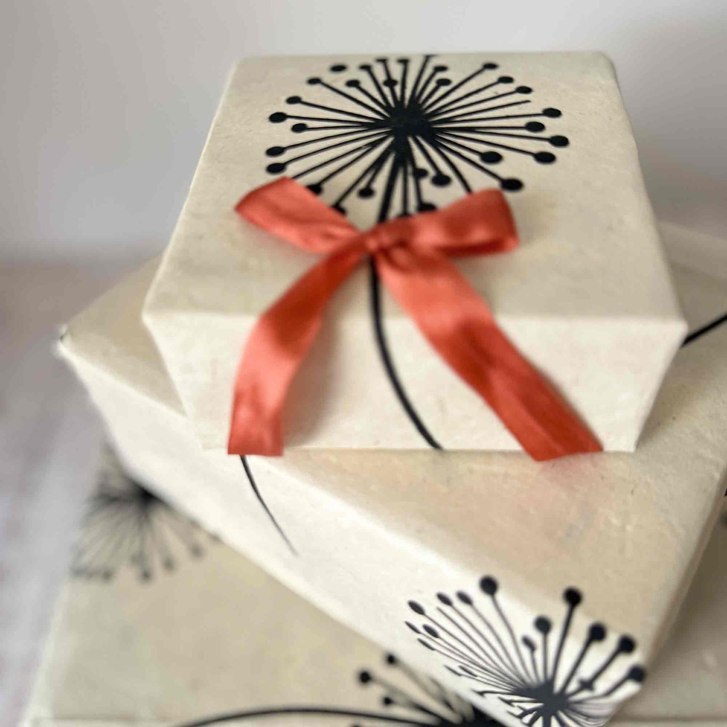 Handmade Lokta paper gift wrap with black dandelion print, wrapped boxes with terracotta ribbon