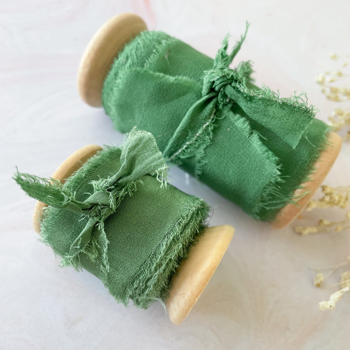 Emerald green silk ribbon on a wooden reel.  Available in 2 sizes.  Luxury ribbon for decorating wedding stationery and invitations.  Silk ribbon also works perfect for floristry projects.  By The Natural Paper Company.