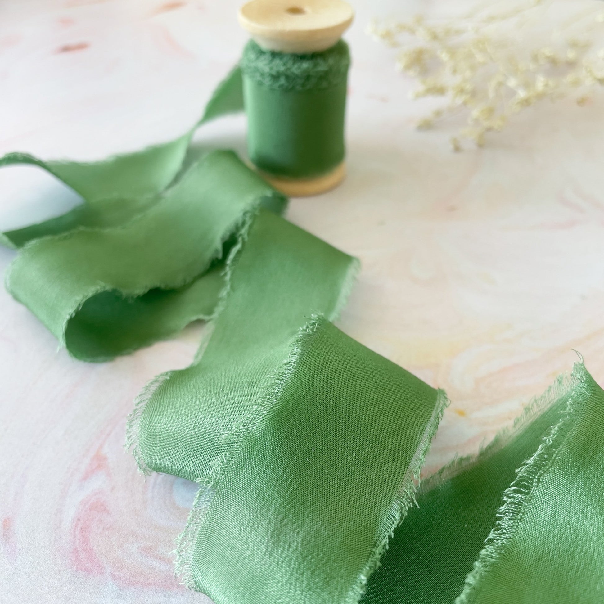 Green silk ribbon with a frayed edge.  Luxury silk ribbon for crafts.  By The Natural Paper Company.