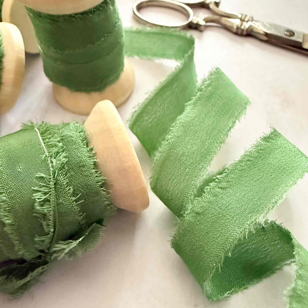 Emerald Green 10mm raw edge silk ribbon with softly frayed edges on wooden reels