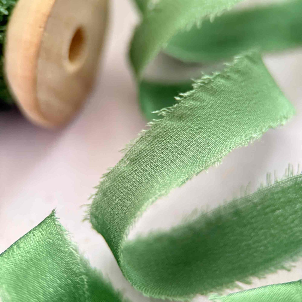 Close-up of Emerald Green 10mm silk ribbon showing soft raw edges