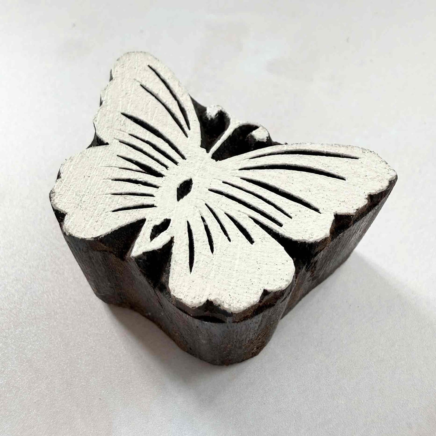 Indian wood block stamp — Flutter butterfly design viewed from angle, showing carved depth and delicate wing vein texture, handcrafted wooden stamp, authentic traditional printing block from India