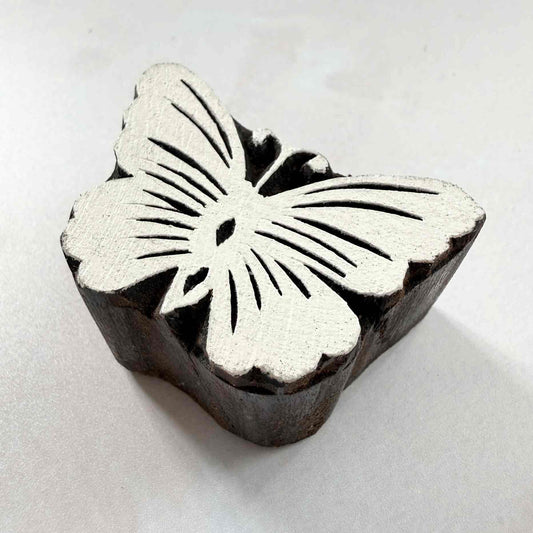 Indian wood block stamp — Flutter butterfly design viewed from angle, showing carved depth and delicate wing vein texture, handcrafted wooden stamp, authentic traditional printing block from India