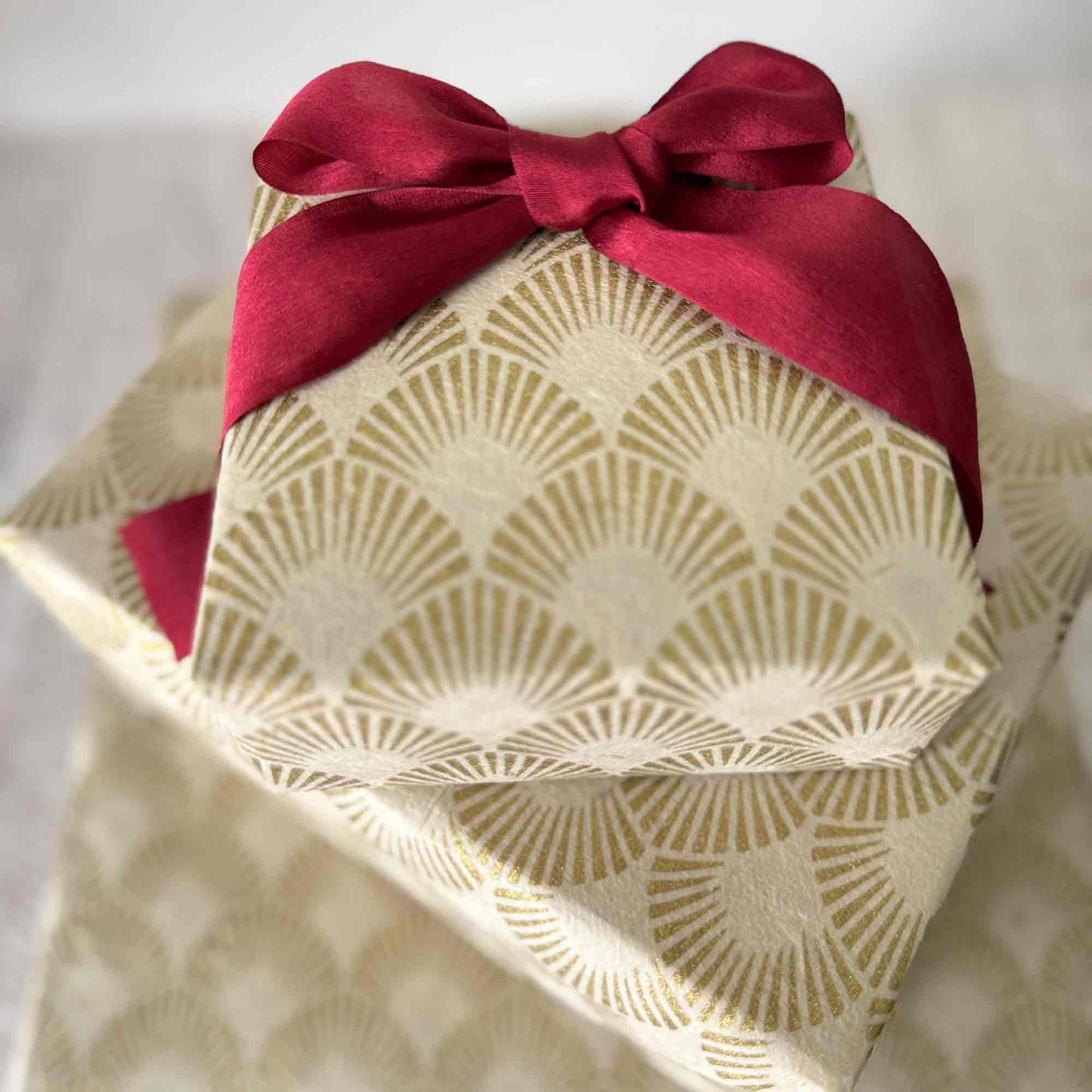 Close-up view of handmade Lokta wrapping paper, hand screen-printed gold fan design on cream paper
