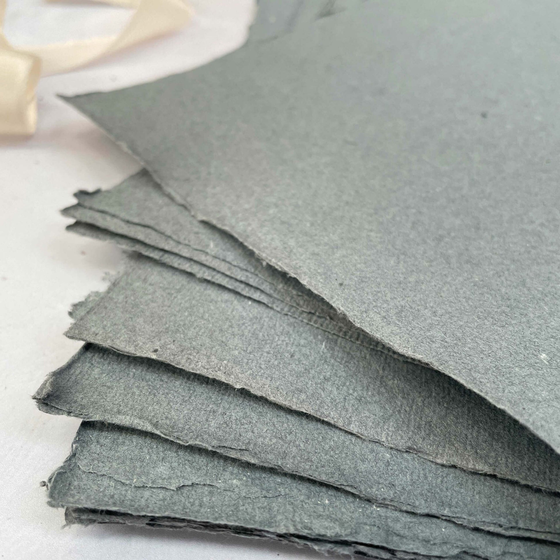 recycled handmade paper made from cotton rag fibres.  Dark grey with deckled edges