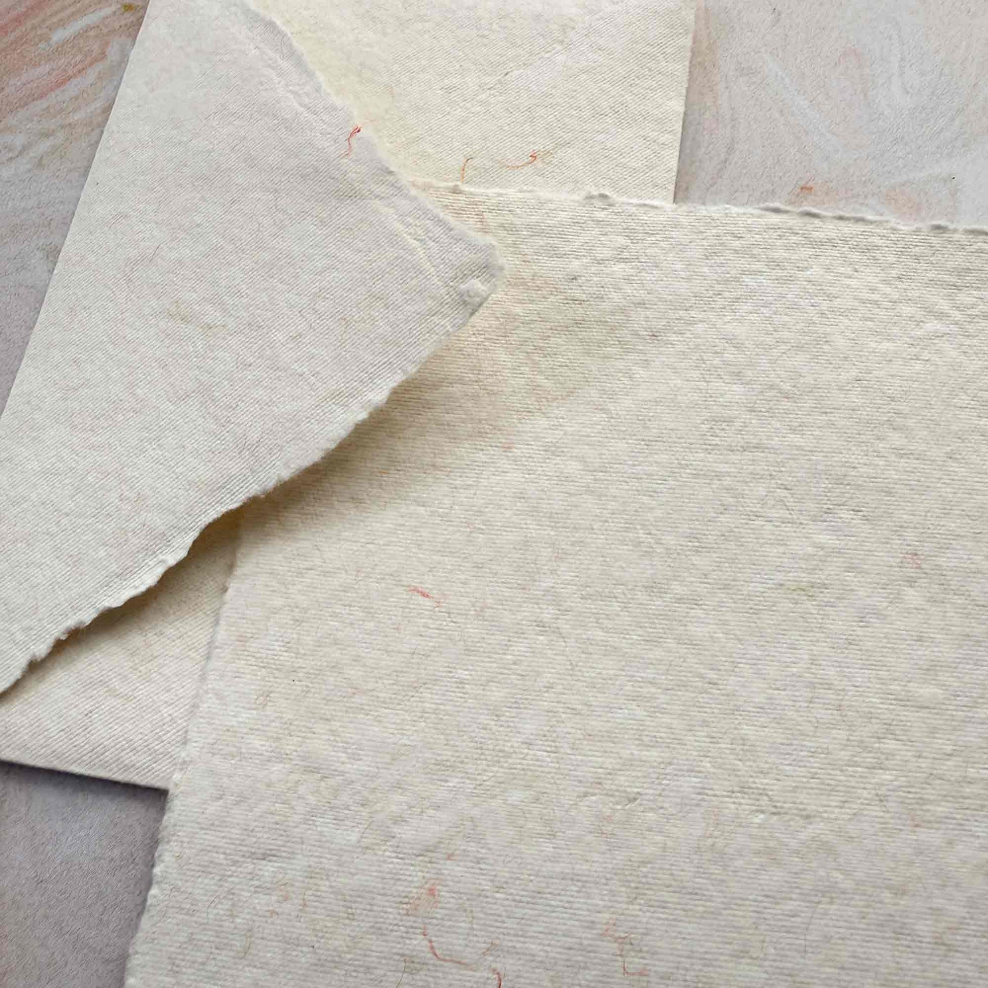 close up picture of handmade cotton paper and matching envelopes with wool fibre decoration