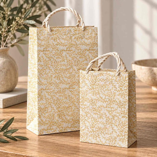 Golden Vine gold botanical Lokta paper gift bags displayed on a wooden table with natural rope handles.