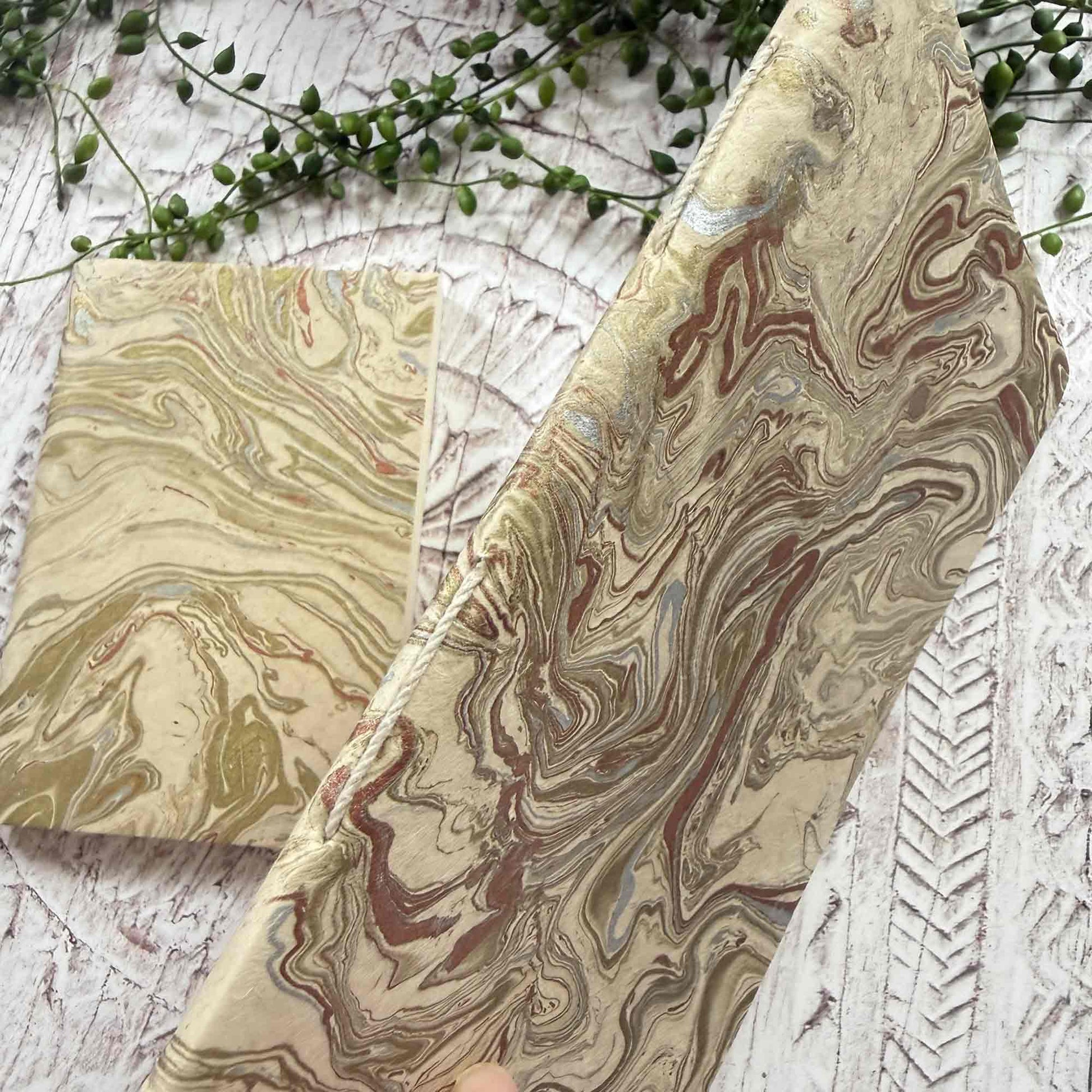 Close‑up of Midas Marble Lokta paper notebook, displaying traditional hand‑stitched spine and intricate hand‑marbled gold and copper pattern