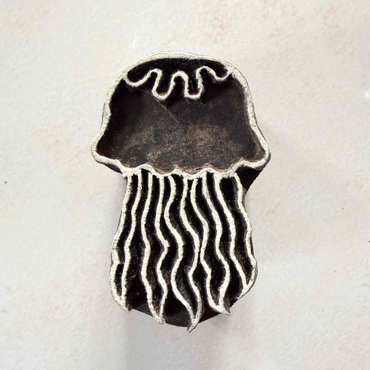 Indian wooden stamp featuring a jellyfish with wavy tentacles and rounded bell