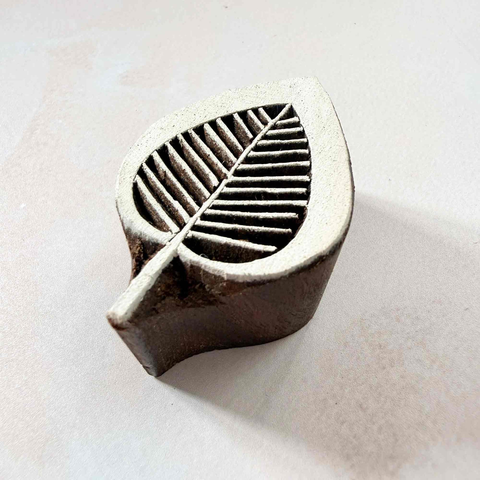 Leaflet Indian wood block stamp — delicate leaf shape viewed from side, showing carved depth and fine vein texture, handcrafted hardwood printing block on neutral background