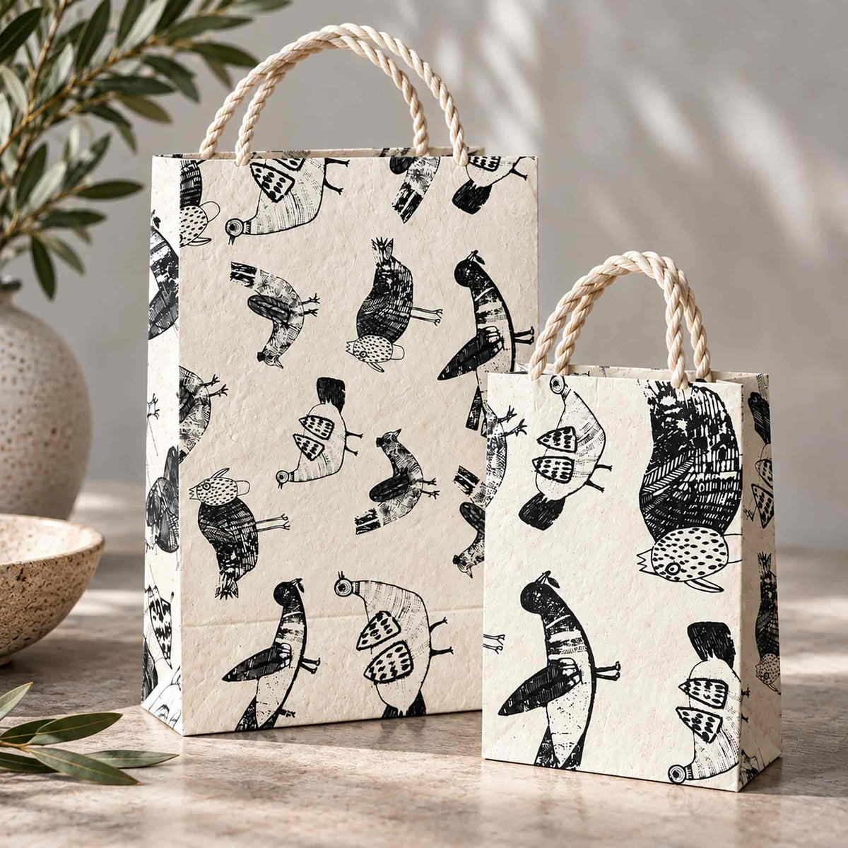 Henrietta chicken print Lokta paper gift bags displayed on a wooden table in a rustic countryside-inspired setting.